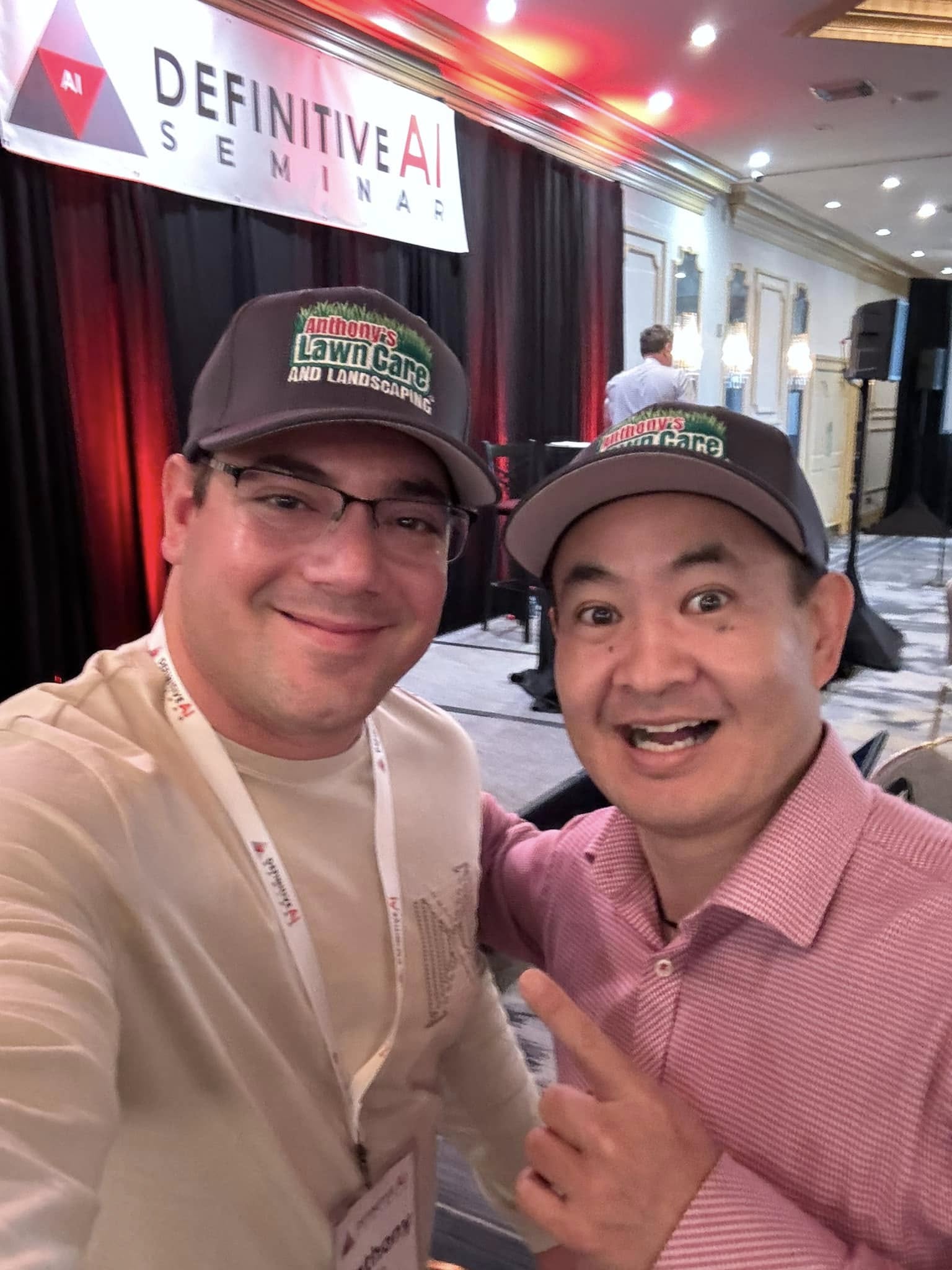 Anthony Hilb and Dennis Yu at the Definitive AI Seminar wearing Anthony's Lawncare and Landscaping caps
