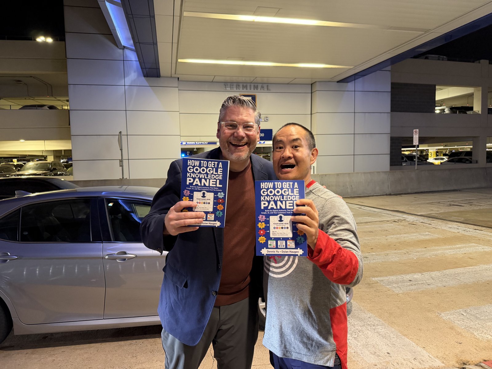 Pete Hazzard and Dennis Yu holding How to Get a Google Knowledge Panel at an airport
